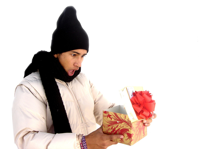 Muž v zimnej čiapke s darčekom, prekvapenie